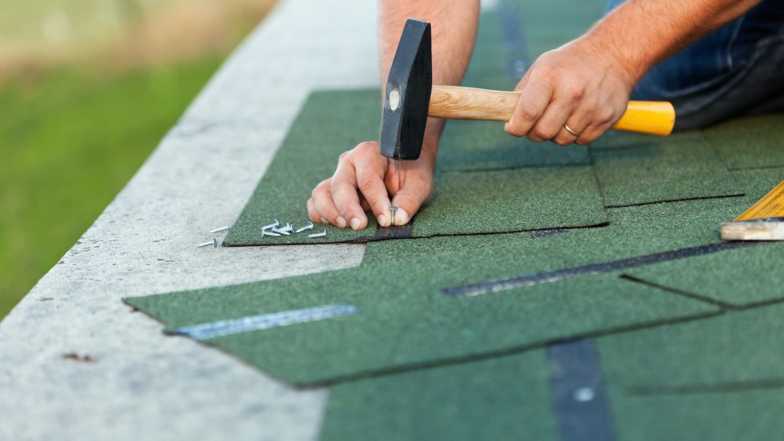 Worker hands installing bitumen roof shingles