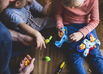 Deux enfants et un homme démontant un jeux de construction