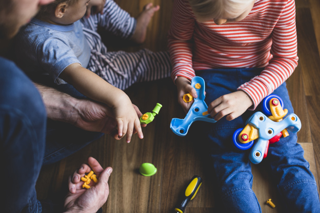 Deux enfants et un homme démontant un jeux de construction