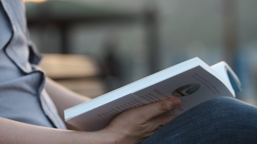 Un homme tient un livre ouvert à la moitié dans ses mains